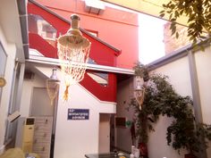 a chandelier hanging from the side of a building next to a table and potted plant