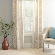 a living room with a chair, window and vase on the floor in front of it