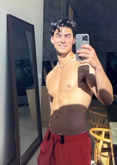 a shirtless man taking a selfie in front of a mirror with his cell phone