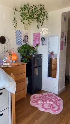 the room is decorated in pink and white with pictures on the wall above the refrigerator