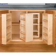 an open cabinet in the middle of a wood floored kitchen with granite counter tops