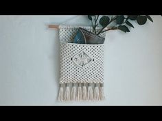 a white wall hanging with a plant in it