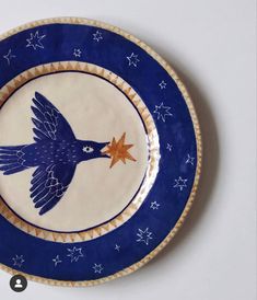 a blue and white plate with a bird painted on it's side in the shape of a star