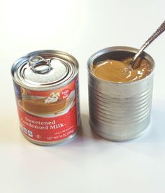 a can of peanut butter with a spoon in it next to a can of nut butter