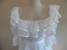 "Vintage 1990s Redux 1950s Short Sleeved; Ruffle Trimmed Wedding Gown, Dress with Full Skirt by Paris Design House, Sasson. This dress is made from a fine white organza and boasts a double satin trimmed ruffle, (top is 4 inches, bottom is 5.5 inches,) on an off-shoulder neckline. The puff sleeves are cinched part way down and have satin trim as well. It has a fitted bodice accented by a satin (attached) belt that buttons in the back with two buttons and elastic loops that have oxidized and need Regency Style Formal Gown With Ruffles, Regency Style Ruffled Wedding Gown, Vintage Wedding Dress With Ruffled Skirt, Vintage Victorian Dress With Ruffles For Debutante Ball, Fitted Victorian Dress With Ruffles For Wedding, White Regency Style Petticoat With Ruffles, Fitted Victorian Wedding Dress With Ruffles, Elegant White Petticoat With Ruffles, Elegant White Ruffled Petticoat