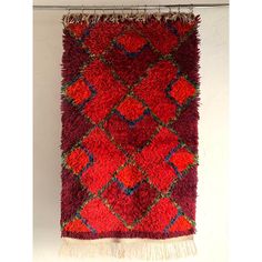 a red rug hanging on a white wall