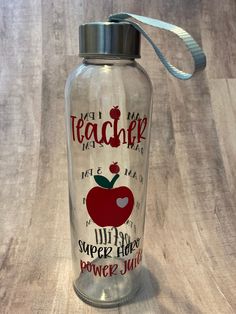 a glass water bottle with an apple on the side that says, not my teacher makes me super happy power juice