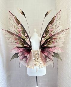 a white mannequin with pink and green wings