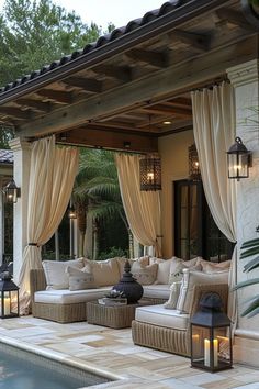 an outdoor living area with couches and lamps next to a swimming pool in front of a house