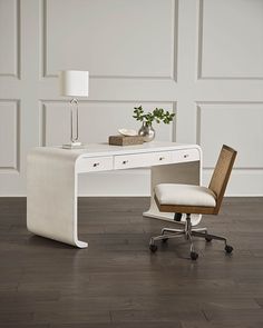 a white desk with a chair next to it on a hard wood floor in front of a wall