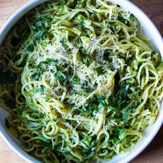 a white bowl filled with pasta and broccoli on top of a wooden table