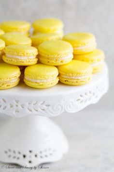 a white plate topped with yellow macaroons on top of a cake platter