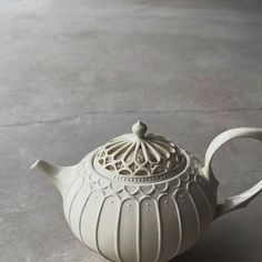 a white tea pot sitting on top of a cement floor