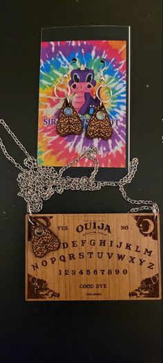 a wooden plaque with an animal on it next to a tie - dyed card and chain