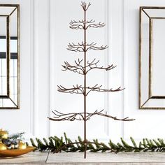 a metal christmas tree sitting on top of a wooden table next to two framed pictures