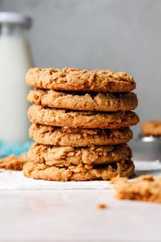 a stack of oatmeal cookies sitting on top of a table next to a glass of milk