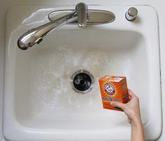 a person is holding a carton of orange juice in front of a white sink