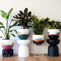 four planters sitting on top of each other in front of a white wall and wooden floor