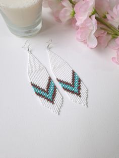 Step into the season with style with our white long beaded earrings, meticulously crafted with precision and care. Inspired by Native American artistry, these earrings feature a bold chevron pattern highlighted with turquoise and brown accents, making them a perfect complement to any Western-style ensemble. The fringe design adds a dynamic touch of movement, ideal for accentuating your summer look. These dangle earrings exemplify boho chic jewelry at its finest, offering both elegance and a whim Earrings Boho Chic, Earrings Western, Beaded Fringe Earrings, Dangle Earrings Boho, Boho Chic Jewelry, Beaded Fringe, Chic Jewelry, Earrings Long, Seed Bead Earrings