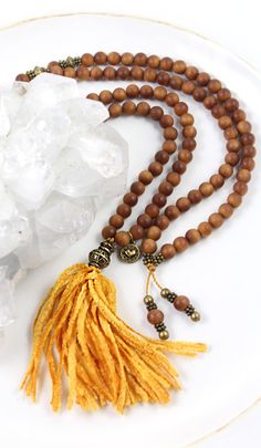 A fragrant lightweight natural Sandalwood mala necklace with 108 beads and a saffron gold chenille tassel. I love the tassel on this mala with its soft velvety touch. It is the traditional saffron gold color of Tibetan Buddhist monks robes (see the last photo). This contemporary mala design is my own, but I feel it somehow has a timeless feel. The fragrance of natural Sandalwood is exquisite! Used for over 4,000 years as an incense, it is a wonderful aid for promoting relaxation and meditative s Natural Wooden Beads Necklace For Meditation, Brown Beaded Holistic Mala, Holistic Brown Beaded Mala, Brown Wooden Beads Holistic Necklace, Holistic Brown Necklaces With Wooden Beads, Holistic Brown Mala With Wooden Beads, Brown Wooden Beads Necklace For Meditation, Spiritual Brown Wooden Beads Mala, Brown Wooden Beads Spiritual Mala