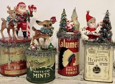 three tin cans with christmas decorations in them and two deer figurines on top