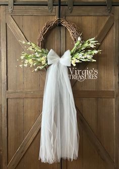 a wreath hanging on the side of a wooden door with a white bow tied to it