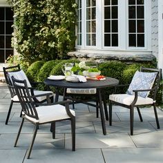 an outdoor dining table and chairs set up on a patio with white trimmings