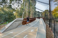 a skateboarder is going down the ramp in an empty area with trees and fencing