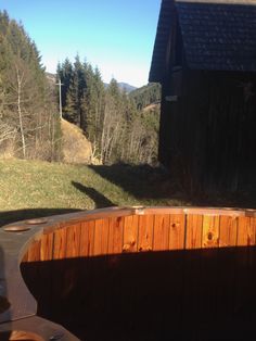 a wooden bench sitting in the middle of a field next to a barn and forest