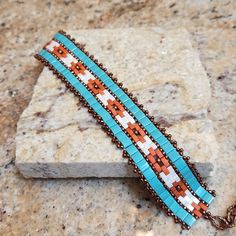 This stunning statement bracelet is handcrafted with glass beads that are woven to create the geometric Southwest design.  The band is approximately 1 inch wide and the bead-woven portion is 6 1/2 inches long.  It can be worn as a 7 inch and up to a 8 1/4 inch size due to the versatile extender chain.  The bracelet features the soft muted colors of a desert palette.  This is truly a unique piece to add to your jewelry collection or to give as a special gift. Desert Palette, Western Bracelets, Southwest Design, Seed Bead Bracelet, Mountain Designs, Glass Bracelet, Western Jewelry, Seed Bead Bracelets, Statement Bracelet