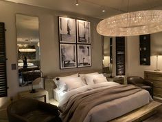 a large bed sitting under a chandelier in a bedroom next to a chair