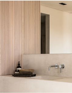 a bathroom sink sitting under a mirror next to a wooden wall