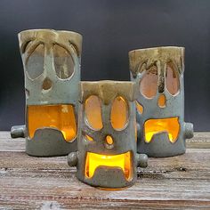 three ceramic candles with faces on them sitting on top of a wooden table next to each other