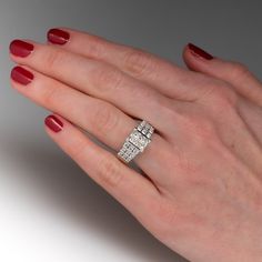 a woman's hand with red nail polish holding a diamond ring