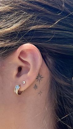 a close up of a person's ear with a small tattoo on the back of their left ear