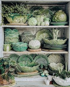 an old cabinet filled with lots of green cabbages and other produce in bowls on top of wooden shelves