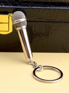 a microphone keychain sitting on top of a table next to a black purse