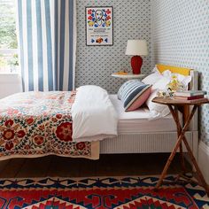 a bed sitting in a bedroom next to a table with a lamp on top of it