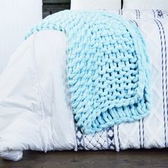 a bed with a blue blanket on top of it next to pillows and pillow cases