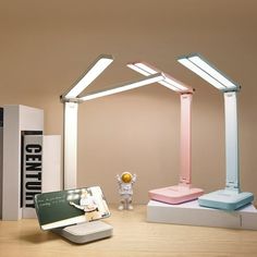 a desk with two lamps and a phone on it, next to a book shelf