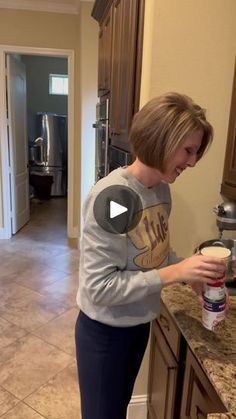 a woman standing in a kitchen with a can of milk on the counter and a blender behind her