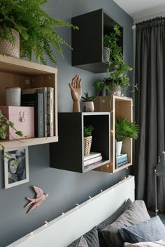 a bedroom with plants and books on the shelves above the bed, along with other decorations