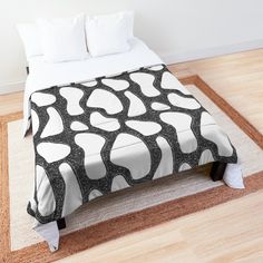 a bed with a black and white design on the comforter is sitting on a wooden floor