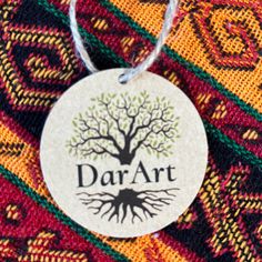 a tree with the word dar art on it is hanging from a colorful fabric background