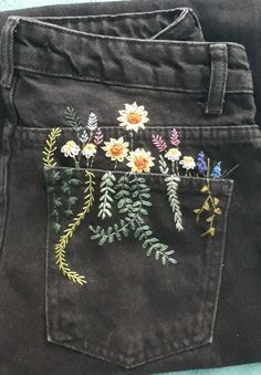 a pair of jeans with embroidered flowers on them