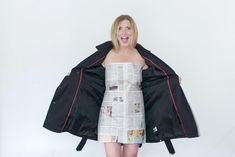 a woman in a newspaper dress holding up a jacket