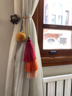 two tassels hanging from the side of a curtain in front of a window