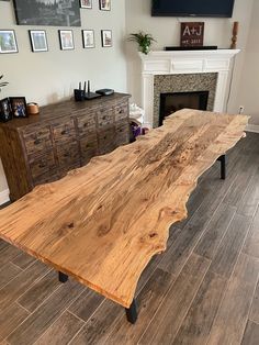 a large wooden table sitting on top of a hard wood floor next to a fireplace