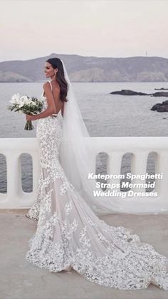 a woman in a wedding dress standing on a bridge looking at the water with her bouquet