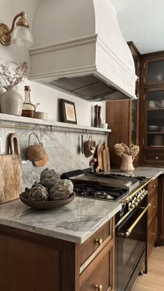 a kitchen with marble counter tops and wooden cabinetry, along with an oven hood